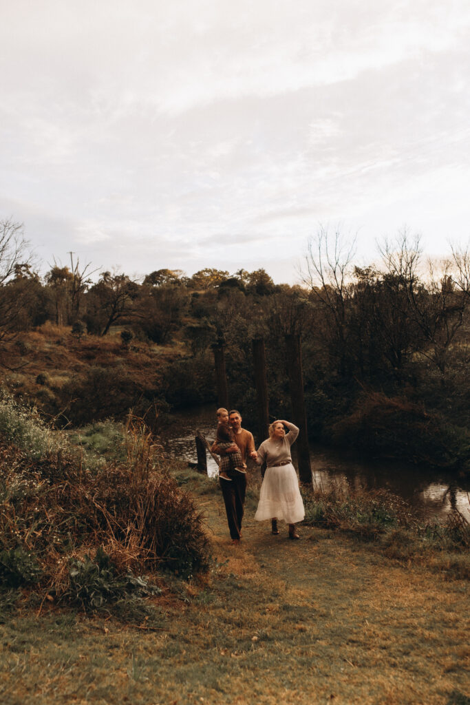 Family of three walking hand in hand along the riverbank in Gympie after a rainy day session.