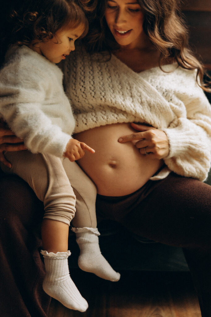 Gympie maternity photographer. Young child pointing to mother’s pregnant belly during intimate maternity photoshoot in Gympie, Sunshine Coast.